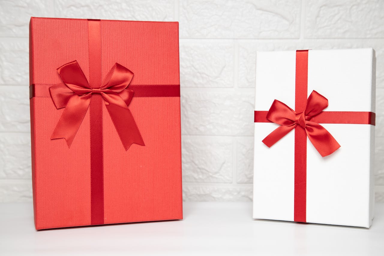 The Art of Drawing Readers In: Your attractive post title goes here Two stylish gift boxes with red ribbons on a white indoor background, perfect for celebrations.